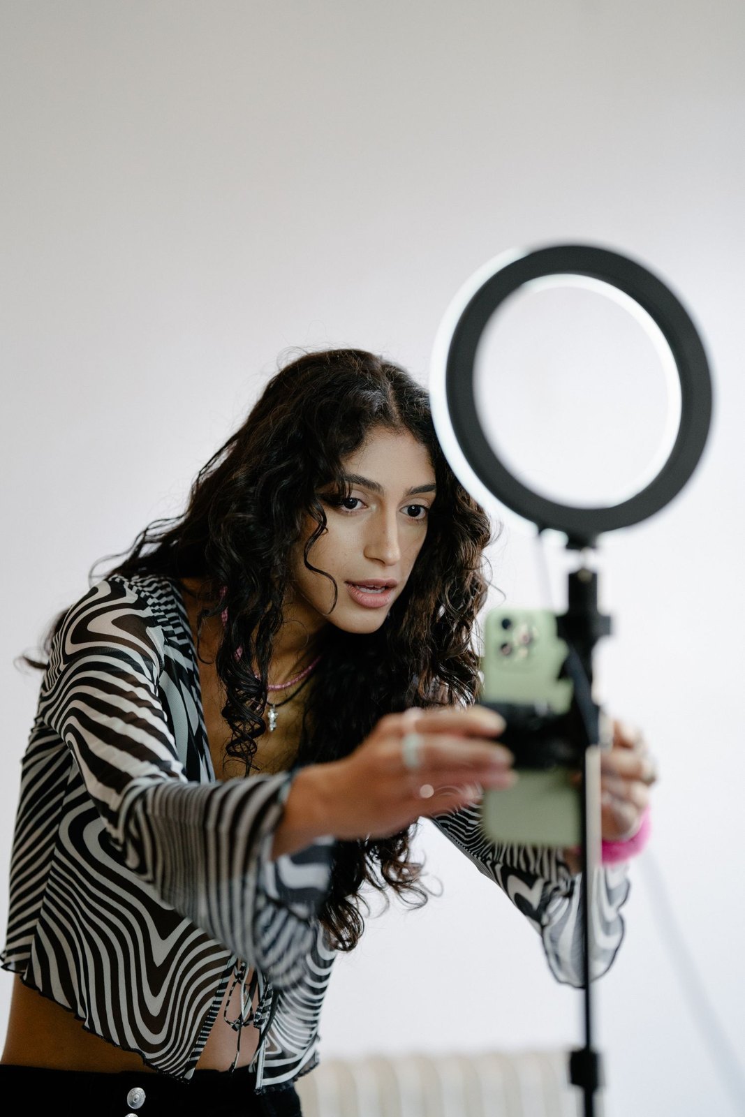 A person setting up a phone and ring light for a self-recorded video.